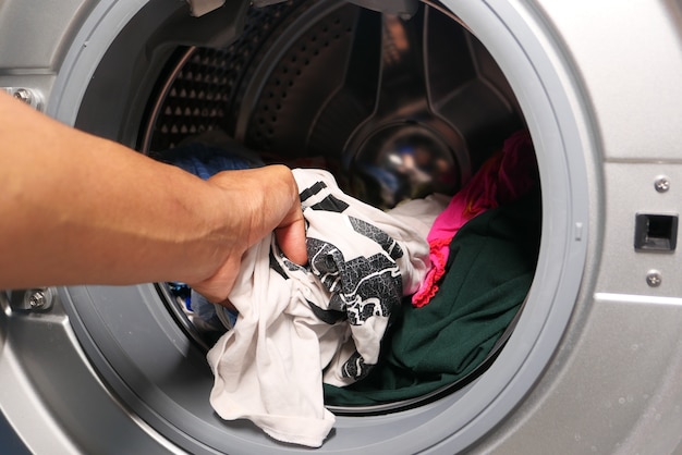 Man putting shirt into washing machine.