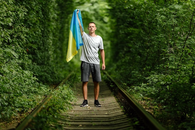 Man raised his hands and holds the Ukrainian flag behind his back concept Ukrainian patriot rally in support of Ukraine