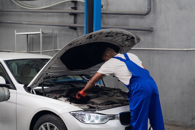 Man raised the hood of a car and inspects the engine