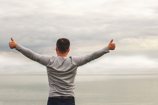 Man raising his arms by a lake