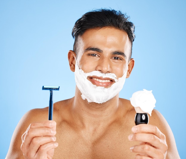 Man razor and shaving cream for skincare grooming or facial treatment against a blue studio background Portrait of a male beard with smile holding cosmetics for shave beauty or hygiene on mockup