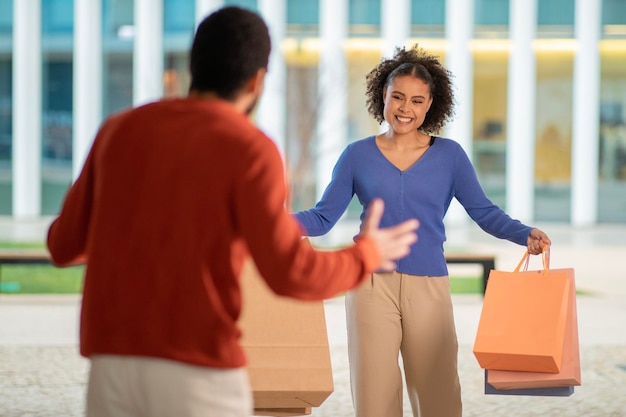 Man reacting negatively to shopaholic woman after shopping outdoor