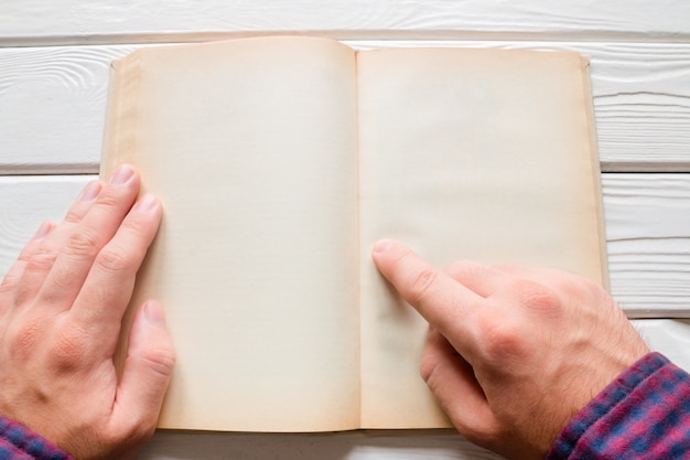 Man reading a book on a white wooden background