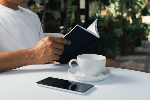 A man reading a book with coffee cup. Man sitting in chair at home, reading book and relaxing.