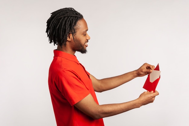 Man reading letter or greeting card, holding envelope, smiling and rejoicing pleasant news.