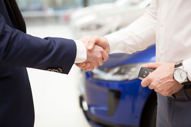 Photo man receiving car keys from salesman at the dealership