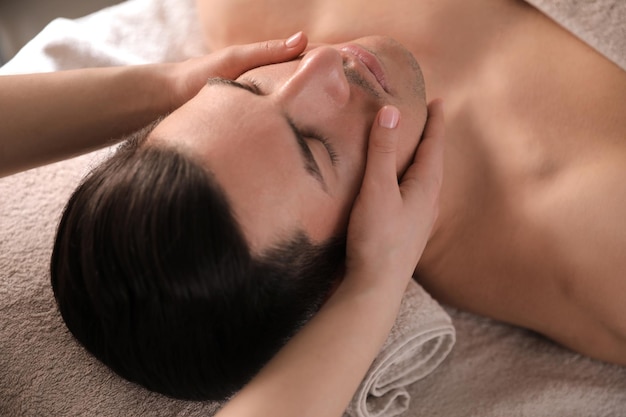 Man receiving facial massage in beauty salon closeup