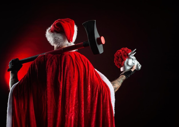 A man in a red Santa Claus Cape with an axe and a metal bull figurine symbol of the new year 2021