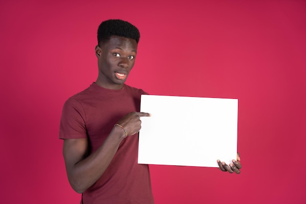 A man in a red shirt is holding a white sign and pointing to it