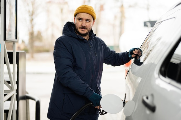 Man refueling his american SUV car at the gas station in cold weather