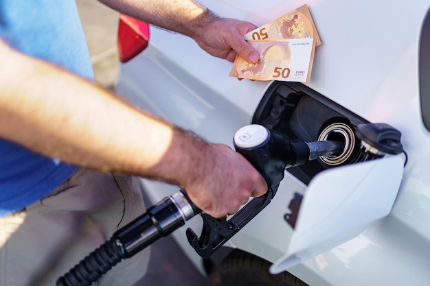 Man refueling with two fifty euro bills for the high price due to inflation