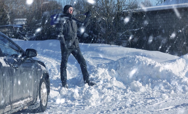 Man remove snow with shovel from the road in snowy winter