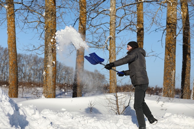 Man remove snow with shovel from the road in winter day