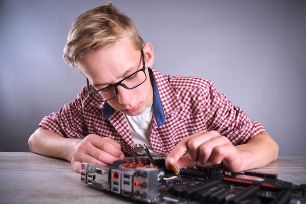 Man repairing broken computer, video card,memory RAM, cooler, processor,hard drive.Young repairer working with screwdriver in service center.teenager