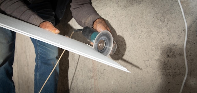 Man repairing ceiling with grinding plastic panel