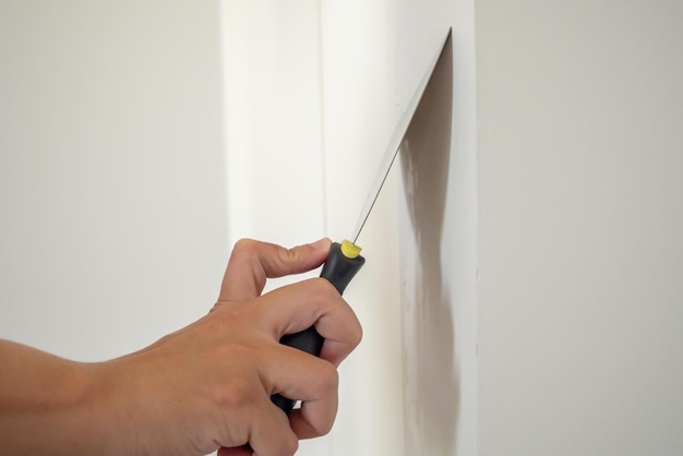 Man repairing crack white wall with spatula