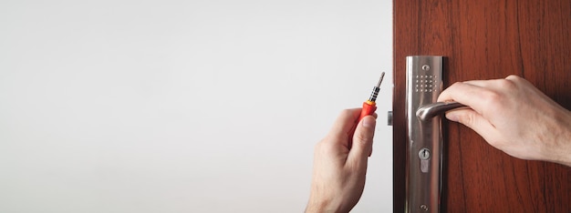 Man repairing door lock Hand of the repairman with a screwdriver