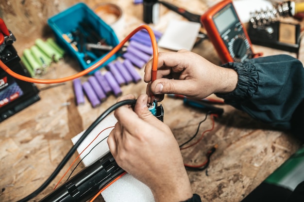 Man repairing electrical scooter in special workshop. Special workshop for repairing electrical scooters and bicycles.