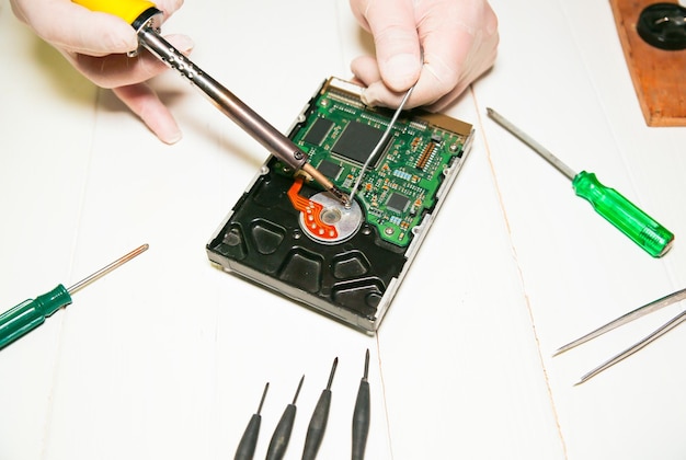 Man repairing hard disk Inside details of the old personal computer Broken PC Soldering iron in hands