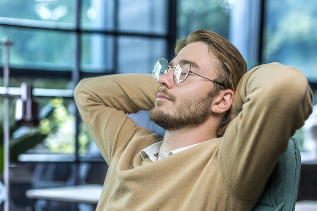 Man resting at home young guy with closed eyes in glasses hands behind head napping during the day