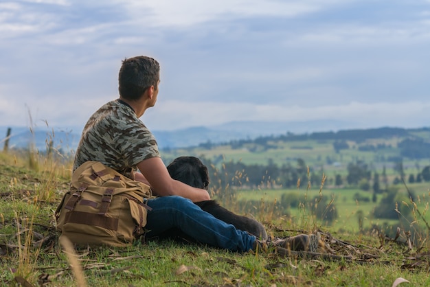 Man resting on the top of a mountain with his dog