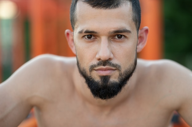 A man rests after doing push UPS on the bars outside at the day close up