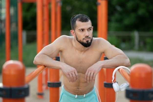 A man rests after doing push UPS on the bars outside at the day