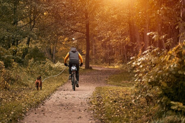 Man rides a bike in the park with his dog