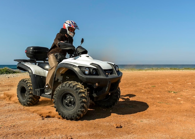 A man riding ATV in sand in protective helmet