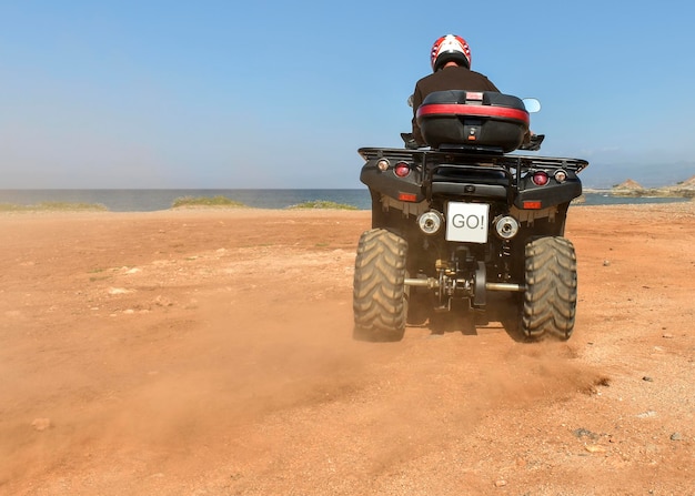 A man riding ATV in sand in protective helmet