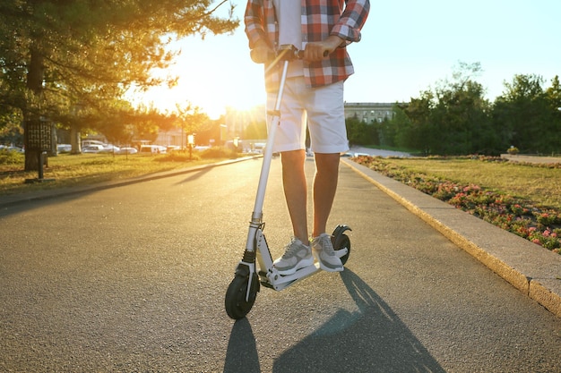 Man riding modern kick scooter in park closeup