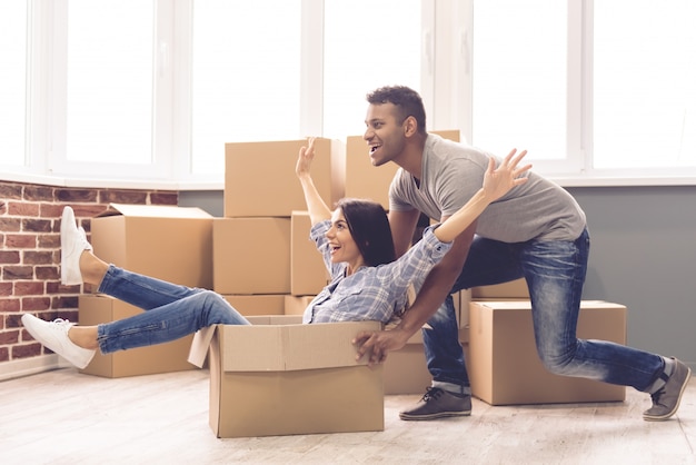 A man rolls a girl in a box in a new apartment.