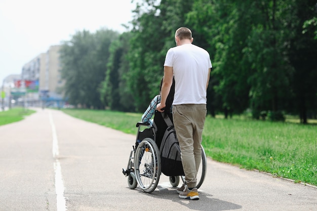 Man rolls wheelchair with girl down street.