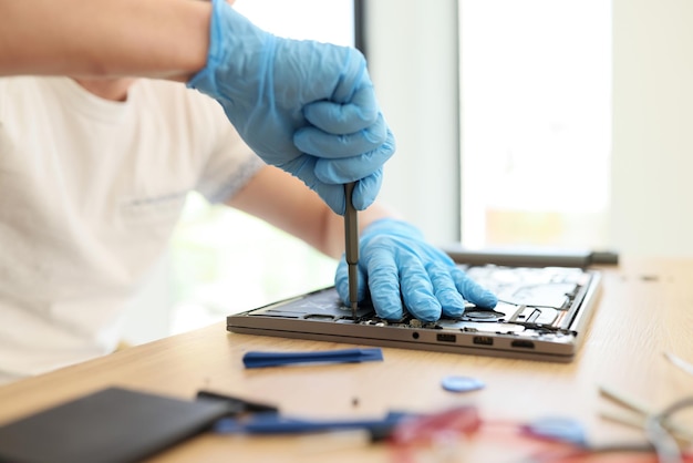 Man in rubber gloves unscrews printed circuit board of broken laptop skilled specialist works