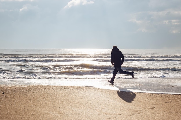 A man running along the sandy beach on a sunny winter day Happy weekend