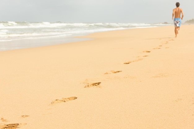 Photo man running on empty wild beach leaving his footprints on the sand in bentota sri lanka