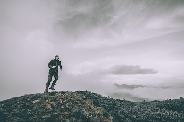 The man running on the mountain on a beautiful clouds background