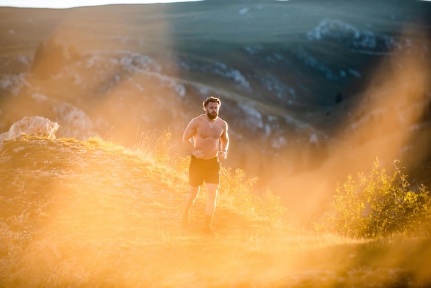 A man running on a mountain in the early morning as the sun rises.