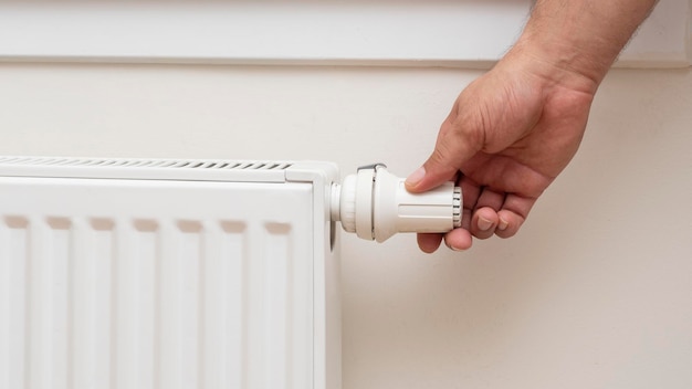 Man's hand adjusting the temperature of a radiator