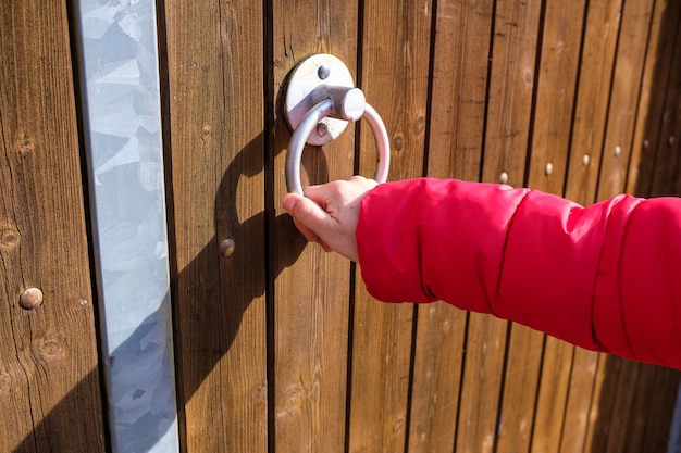 Man's hand closing or opening a rusty old wooden door