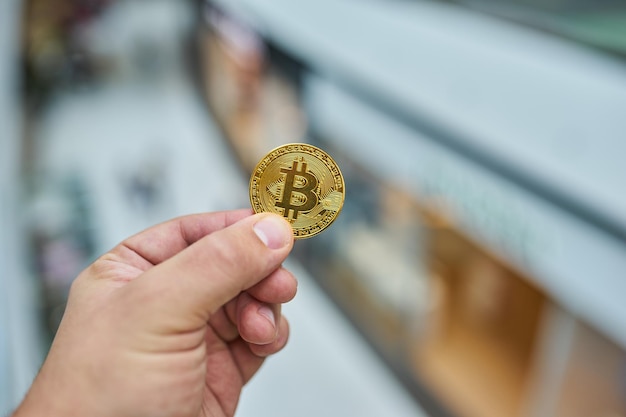 Man's hand holding golden Bitcoin