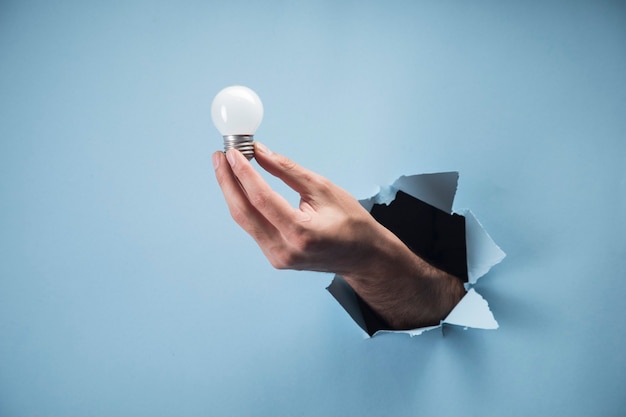 Man's hand holding a lamp on a blue scene