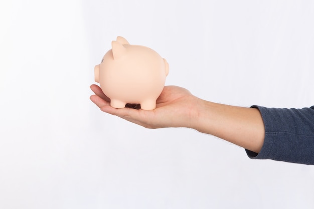 Man's hand holding a pink piggy bank isolated on white background