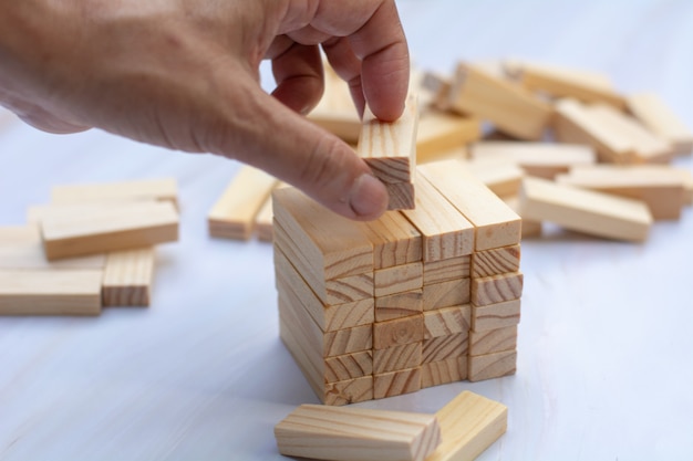 Man's hand holding a top of wooden blocks over wooden block