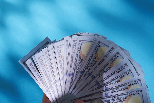 Man's hand holds american dollars money On blue background Finance earnings crediting