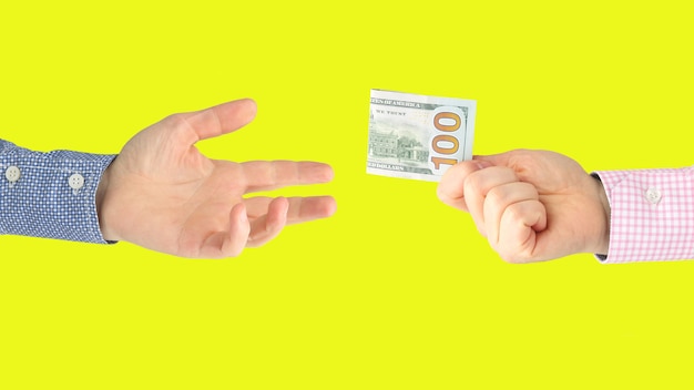 Man's hand holds out a fork with a dollar bill in the other hand on yellow 