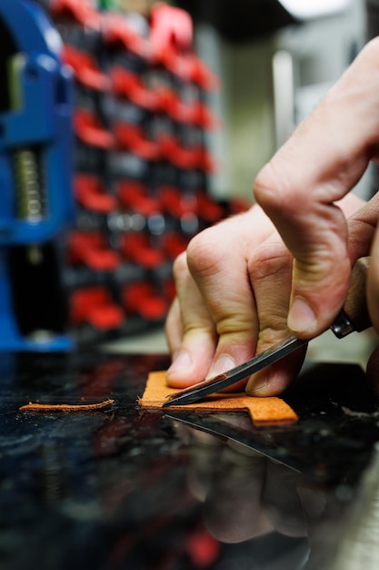 A man's hand holds pieces of leather for a leather wallet in his workshop The process of working with natural brown leather The craftsman holds the craft