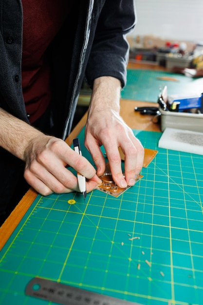 A man's hand holds pieces of leather for a leather wallet in his workshop The process of working with natural brown leather The craftsman holds the craft