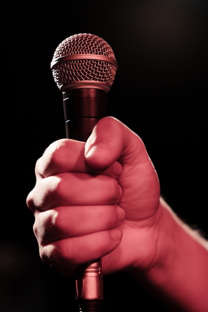 A man's hand holds a professional microphone