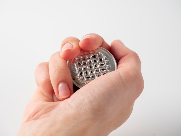 A man's hand holds a used aluminum coffee capsule on a white background. Modern ways of storing coffee